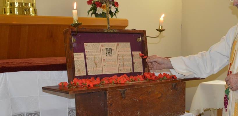 Father Paul Mercovitch laying a poppy on the portable altar, Patchewollock 2015  Diocese of Ballarat
