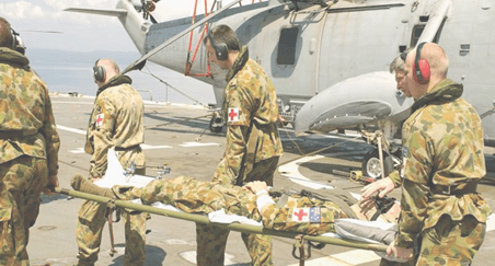 An injured medic is carried by his team to a US helicopter for onward movement
