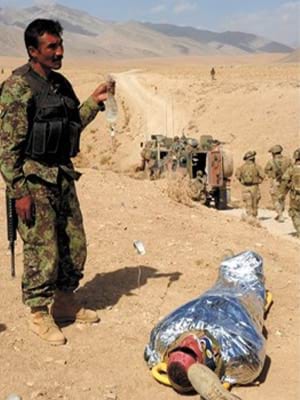 An Afghan National Army soldier holds Chris May’s intravenous drip 23 September 2011