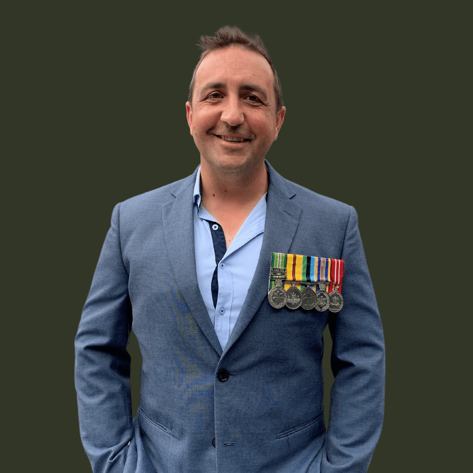 Ron Schultz, wearing a suit and smiling at the camera with his service medals. 