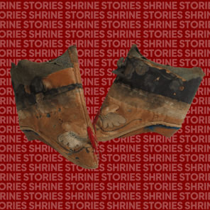 A pair of faded Lotus Shoes. The shoes are a very faded red with a black band around the top. On the toe of the shoe are butterfly wings and some strands of red threat. 