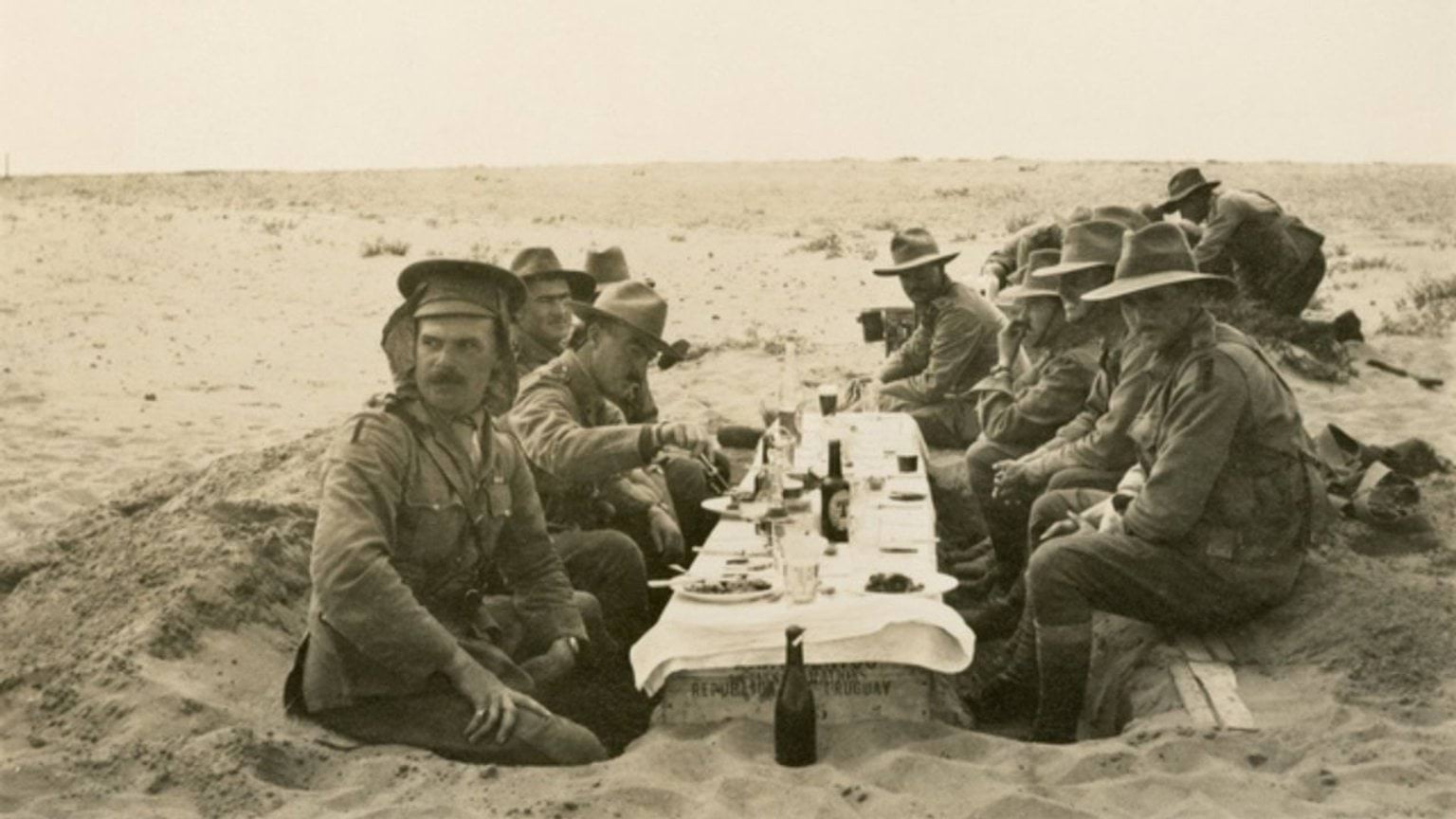 First World War Australian soldiers eating lunch in the desert at an improvised table setting dug into the sand.