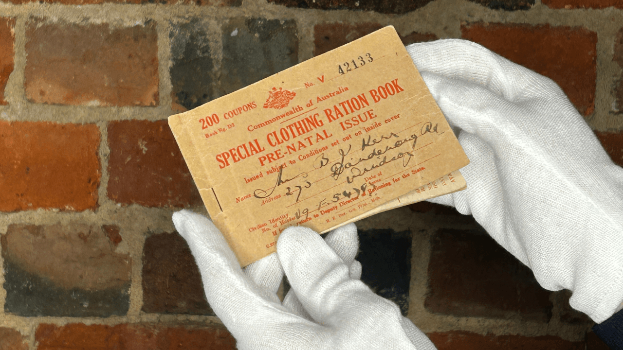 A small book from the Second World War being held in front of a brick wall.