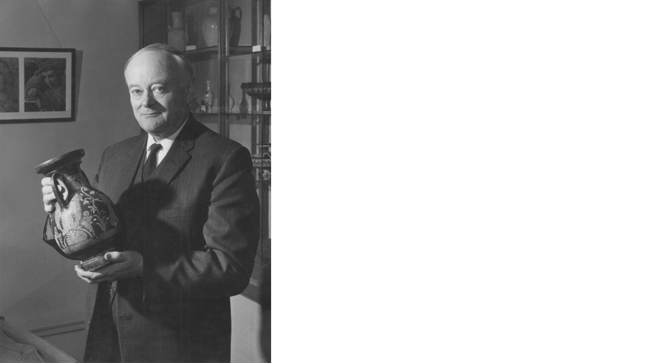 Black and White photograph of Professor A.D. Trendall, standing in an office holding a South Italian vase