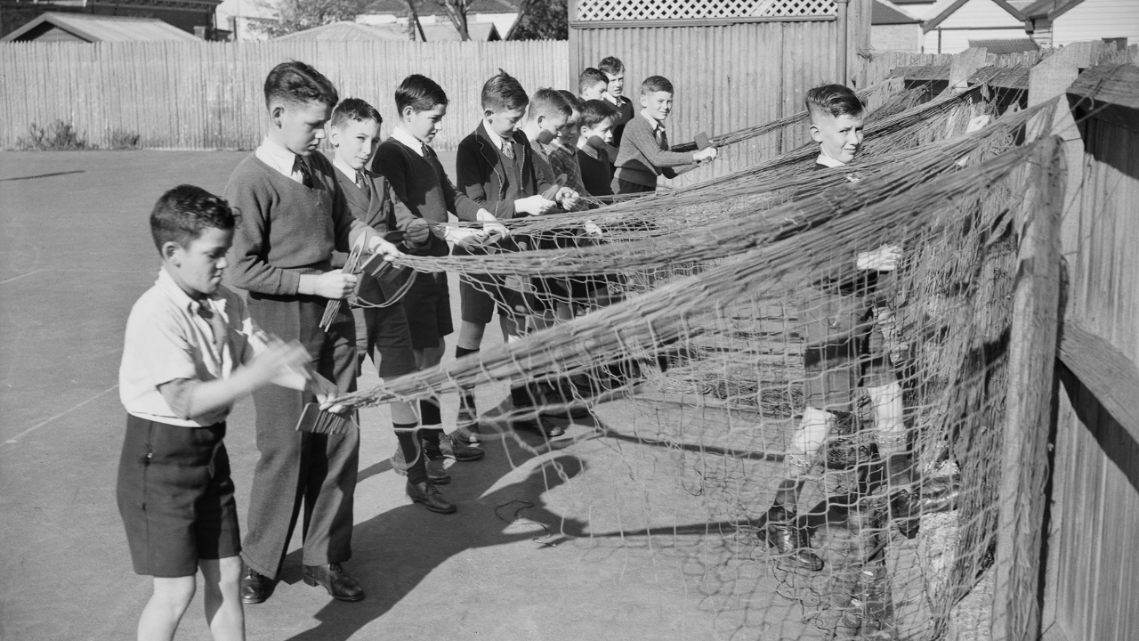 Black and white image of students knotting camouflage nets during the Second World War.