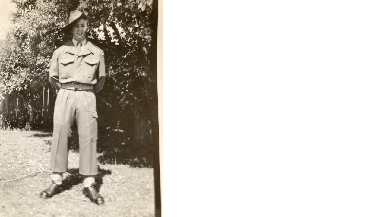 Black and white portrait of a young man standing in a yard wearing a national service uniform