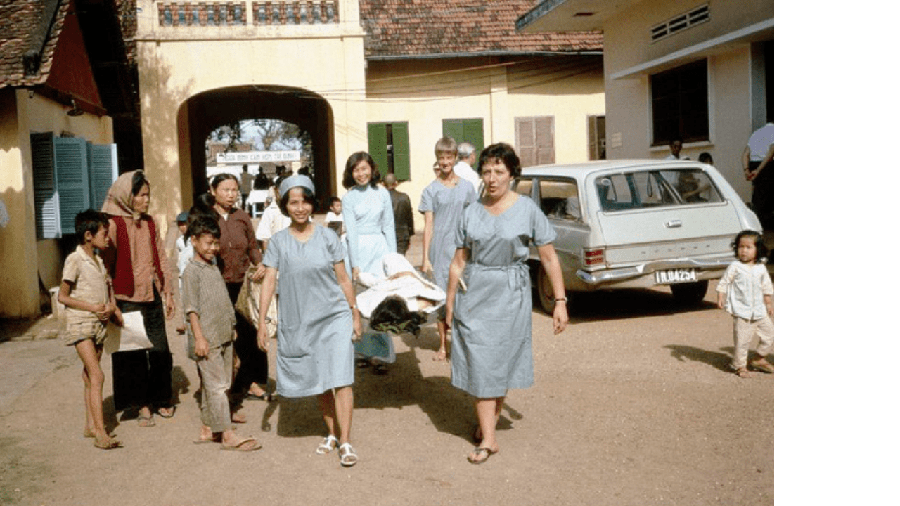 Sister Dorothy Angell (back right) and Sister Pamela Matenson (front right) transporting a patient from the surgical suite to the ward, assisted by two Vietnamese staff in the recovery ward.