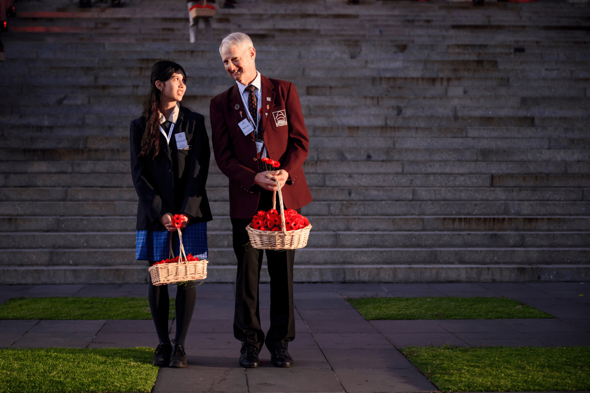 Two volunteers standing in front of steps holding baskets of flowers.