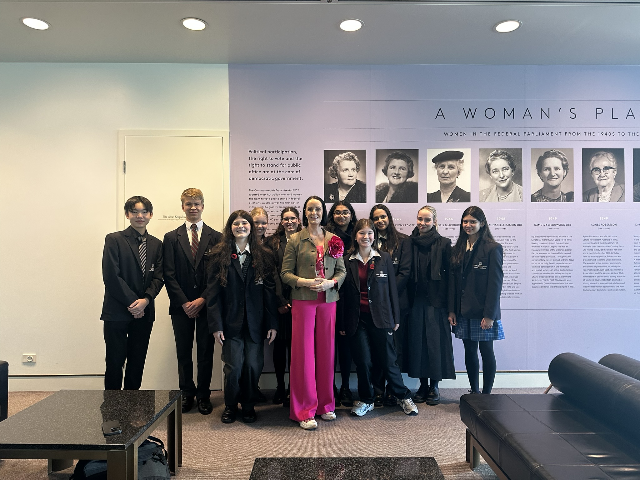 Group of students with MP in an office space, a mural is behind them.