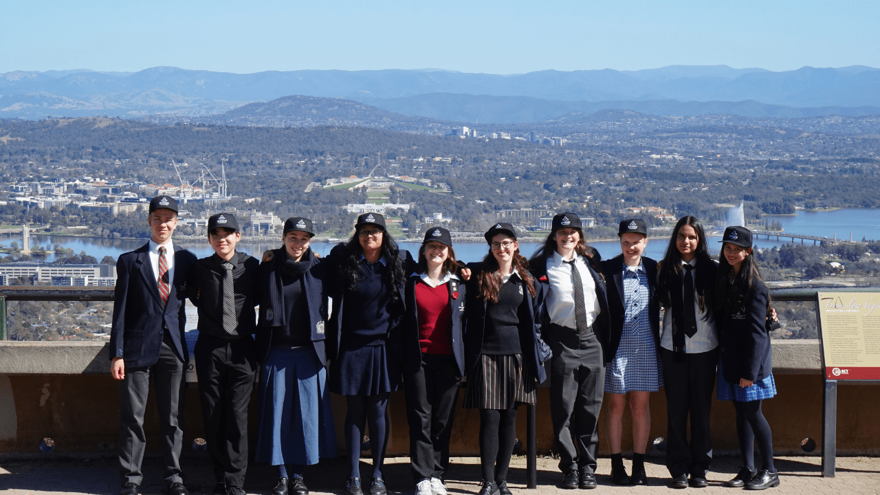 Students posing for a group photo with a scenic city background